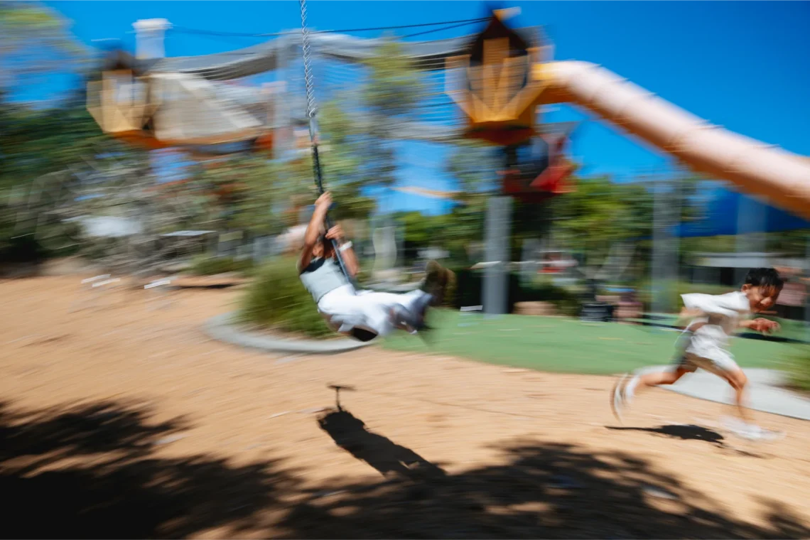 Children playing on a rope swing and slide at a playground